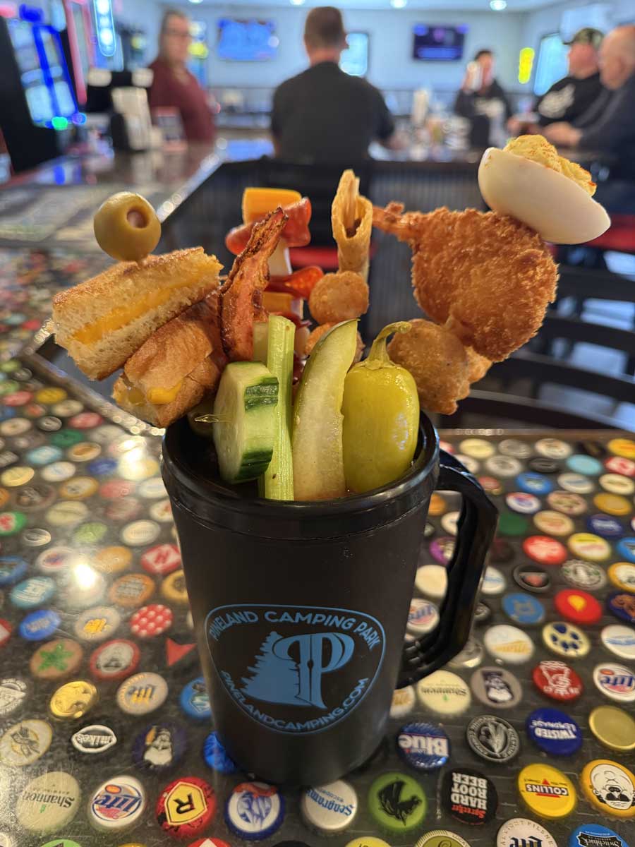 A meal in a glass! 20 oz. Double Bloody Mary made with your choice of vodka and our signature Bloody Mary mix & seasonings. Loaded with a grilled cheese, mini taco, bacon strip, tater tots, jumbo shrimp, pepperoni, cheeses & more! Comes in a keepsake reusable Pineland Grille Mug A meal in a glass! 20 oz. Double Bloody Mary made with your choice of vodka and our signature Bloody Mary mix & seasonings. Loaded with a grilled cheese, mini taco, bacon strip, tater tots, jumbo shrimp, pepperoni, cheeses & more! Comes in a keepsake reusable Pineland Grille Mug.